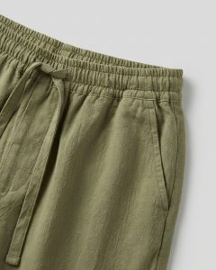 Olive green oversized cotton pant with elastic waistband and adjustable drawstring, shown in close-up fabric detail