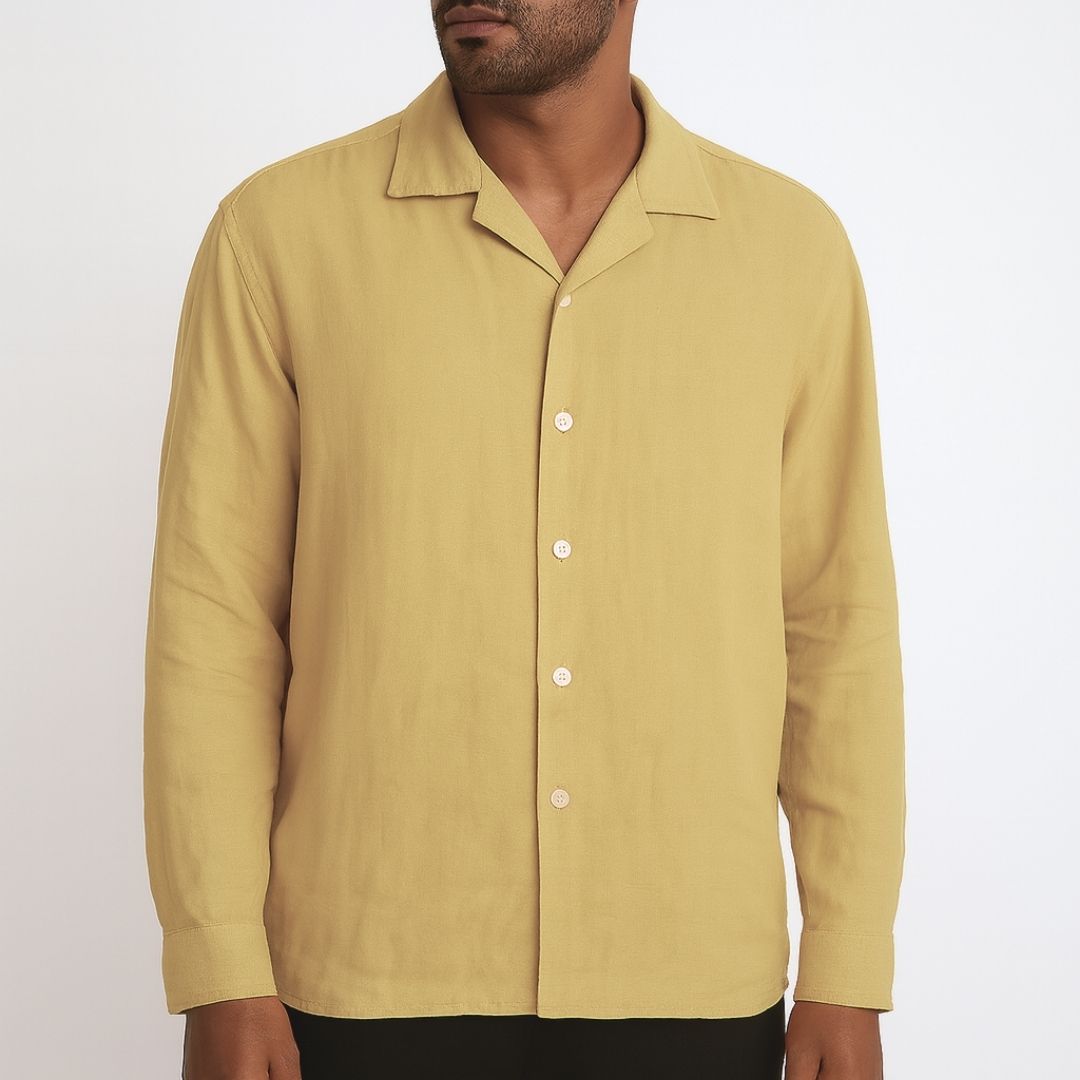 Relaxed Linen Shirt Collection – Black, Harvest Gold & Ivory | Lans Stack of three linen shirts in black, harvest gold, and ivory placed on a wooden stool — part of Lans’ Relaxed Cuban Collar Linen Collection