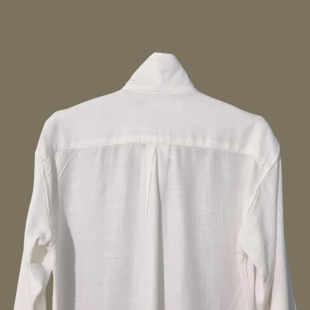 Relaxed Linen Shirt Collection – Black, Harvest Gold & Ivory | Lans Stack of three linen shirts in black, harvest gold, and ivory placed on a wooden stool — part of Lans’ Relaxed Cuban Collar Linen Collection