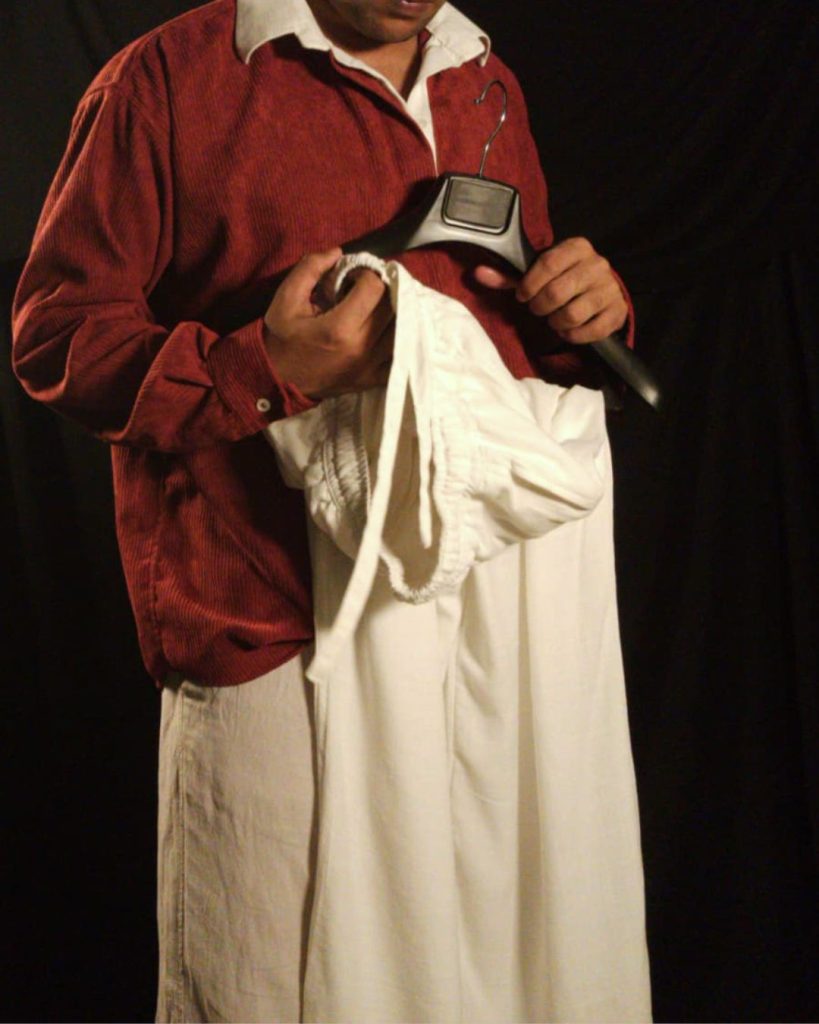 Generic male model wearing an oversized maroon corduroy retro long sleeve shirt with an off-white linen collar and oversized off-white linen drawstring pants on a plain studio background.