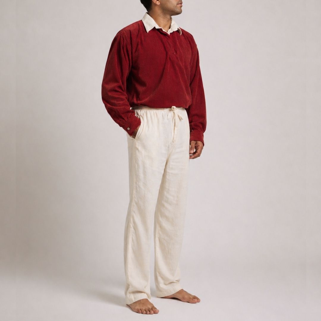 Generic male model wearing an oversized maroon corduroy retro long sleeve shirt with an off-white linen collar and oversized off-white linen drawstring pants on a plain studio background.