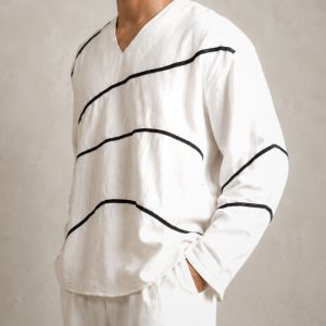 LANS Oversized Wave Runner white cotton V-neck shirt with black piping lines paired with oversized washed cotton pant in a light cement studio background.