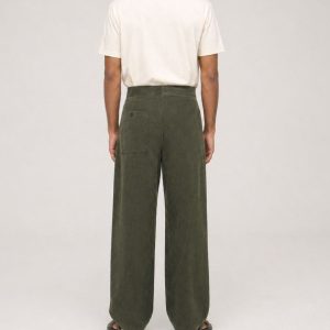 male model wearing dark olive green oversized corduroy Aldo pant with an off-white t-shirt on a plain studio background.