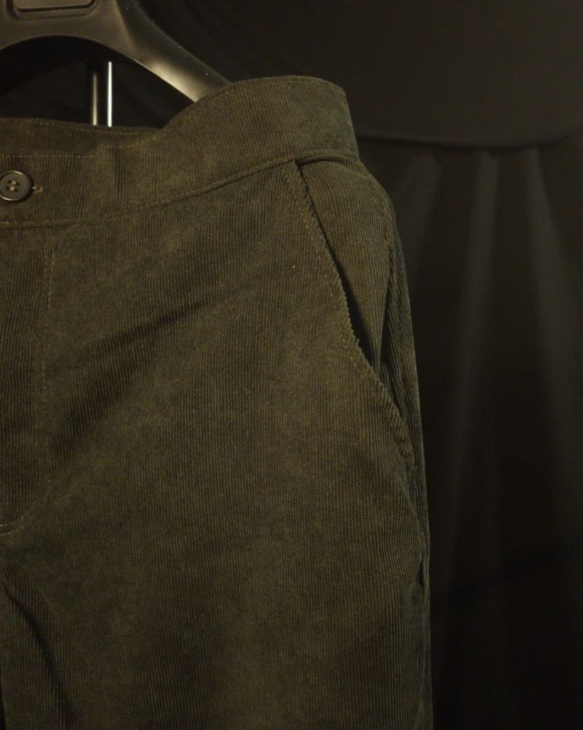 Dark olive green oversized corduroy Aldo pant with structured waistband, front button closure, slanted pockets, and straight-leg fit on a clean white flat lay background.